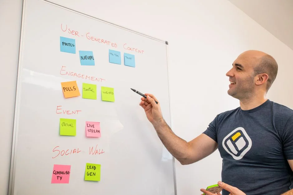 Person analyzes stock data with a smartphone and laptop, indoors.